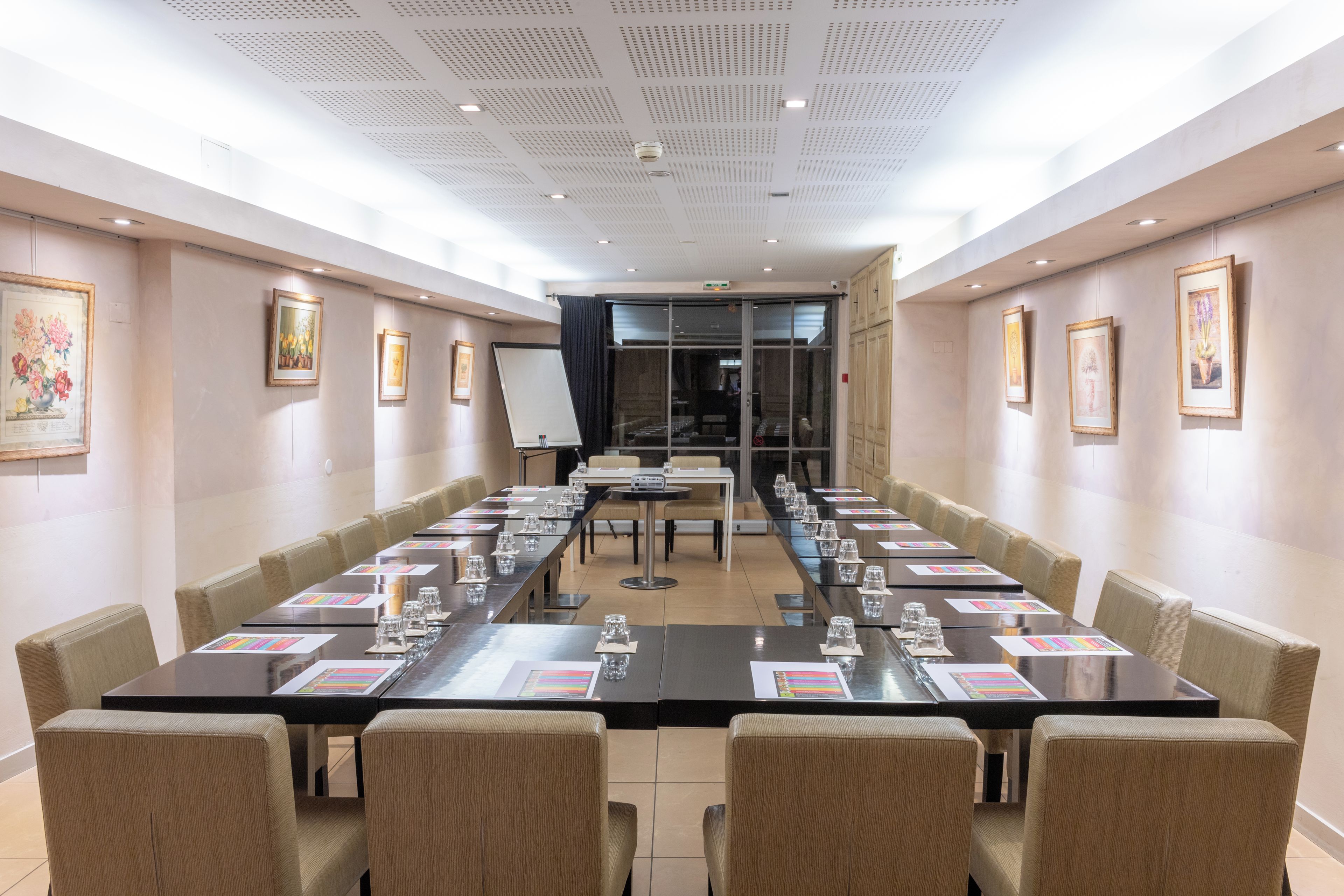 Une salle de conférence avec une longue table, des chaises et des œuvres d’art encadrées accrochées aux murs.