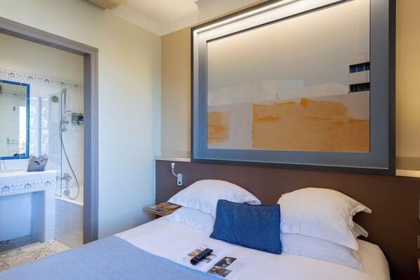 A hotel room with a bed, a bedside table, a nightstand, a mirror, and a shower area. - Hotel Spa Le Calendal (Arles)
