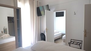 A bedroom with a bed, a desk, a chair, and a TV mounted on the wall. - Logis Hôtel Villa Victorine (Nice)