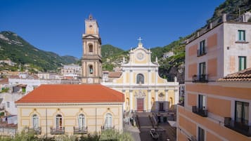 A historic church with a bell tower and a clock, surrounded by buildings and a hillside.