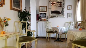 Une pièce meublée de meubles anciens, notamment un fauteuil recouvert d’un tissu vert, une table avec une nappe en dentelle et un miroir doté d’un cadre orné.