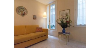 Un canapé jaune dans une pièce où se trouve un vase de fleurs sur une petite table.