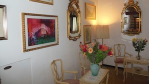 Une pièce comprenant une table, des chaises, un vase avec des fleurs et plusieurs œuvres d’art encadrées accrochées au mur.