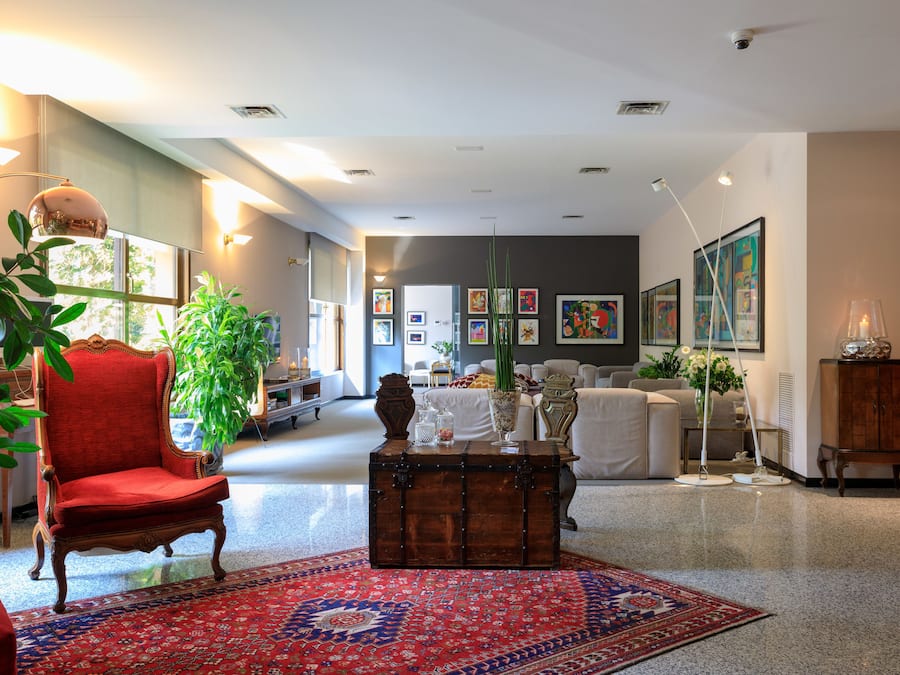 Un salon spacieux avec un fauteuil rouge, une commode en bois et un grand tapis.