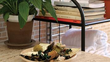 Una encimera de cocina con un bol de diversos aperitivos, una planta en maceta y una estantería con libros y otra planta.