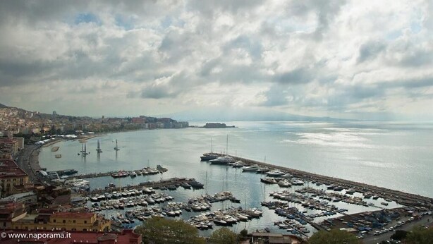 A marina with numerous boats docked, a waterfront promenade, and a cityscape in the background. - Luna Caprese (Naples)