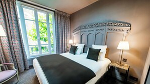 Una cama grande con cubrecama negro, dos lámparas de noche y un cabecero decorativo.