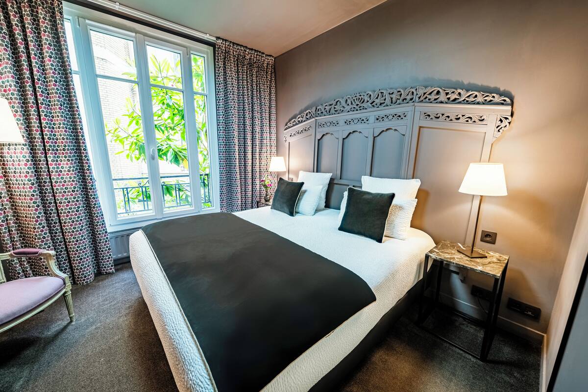 A large bed with a black bedspread, two bedside lamps, and a decorative headboard.