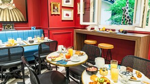 Comedor con paredes rojas, una pintura grande, fotografías enmarcadas y vistas a una jirafa afuera.