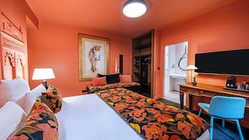 Habitación de hotel con una cama grande, un escritorio con silla, un espejo y una puerta que da a un baño.