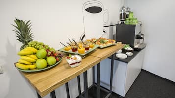 A breakfast buffet with fruits, juices, and a coffee station.