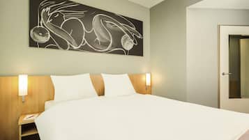 A hotel room with a large bed, two bedside tables, a wall-mounted artwork, and a door.