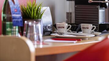 A coffee station with two cups labeled 'COSTA' and a sign offering free coffee.