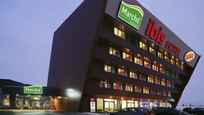 Un hotel con diseño moderno, que presenta un llamativo letrero del restaurante Marche y el logotipo de ibis.