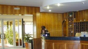 Un área de recepción con un mostrador de madera, una puerta de cristal y una planta en maceta.