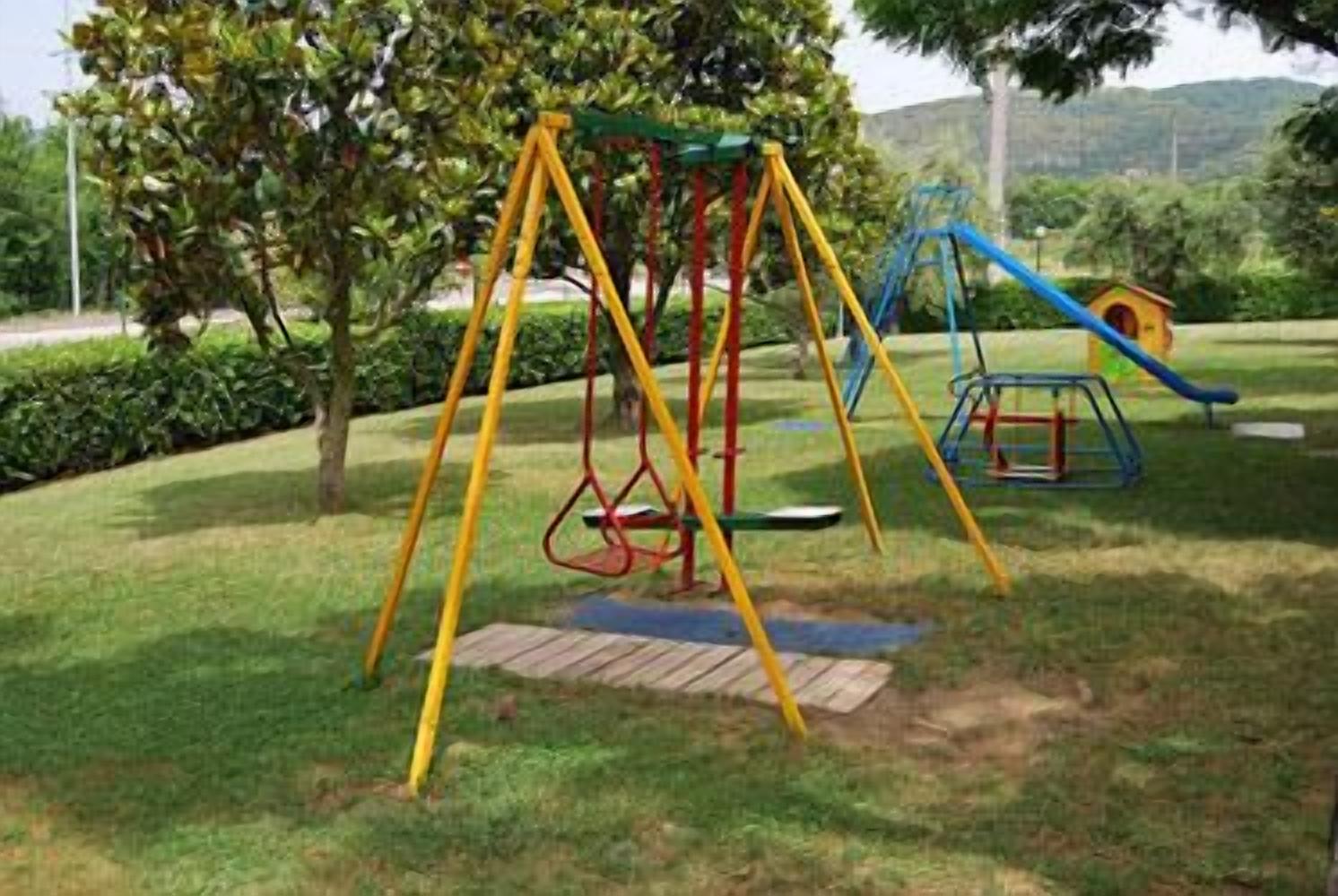 Un parque infantil con columpios y un tobogán.