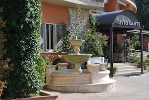 Una fuente con un cartel que indica 'Hotel Piscina' y un edificio con un letrero que dice 'Ristorante'.