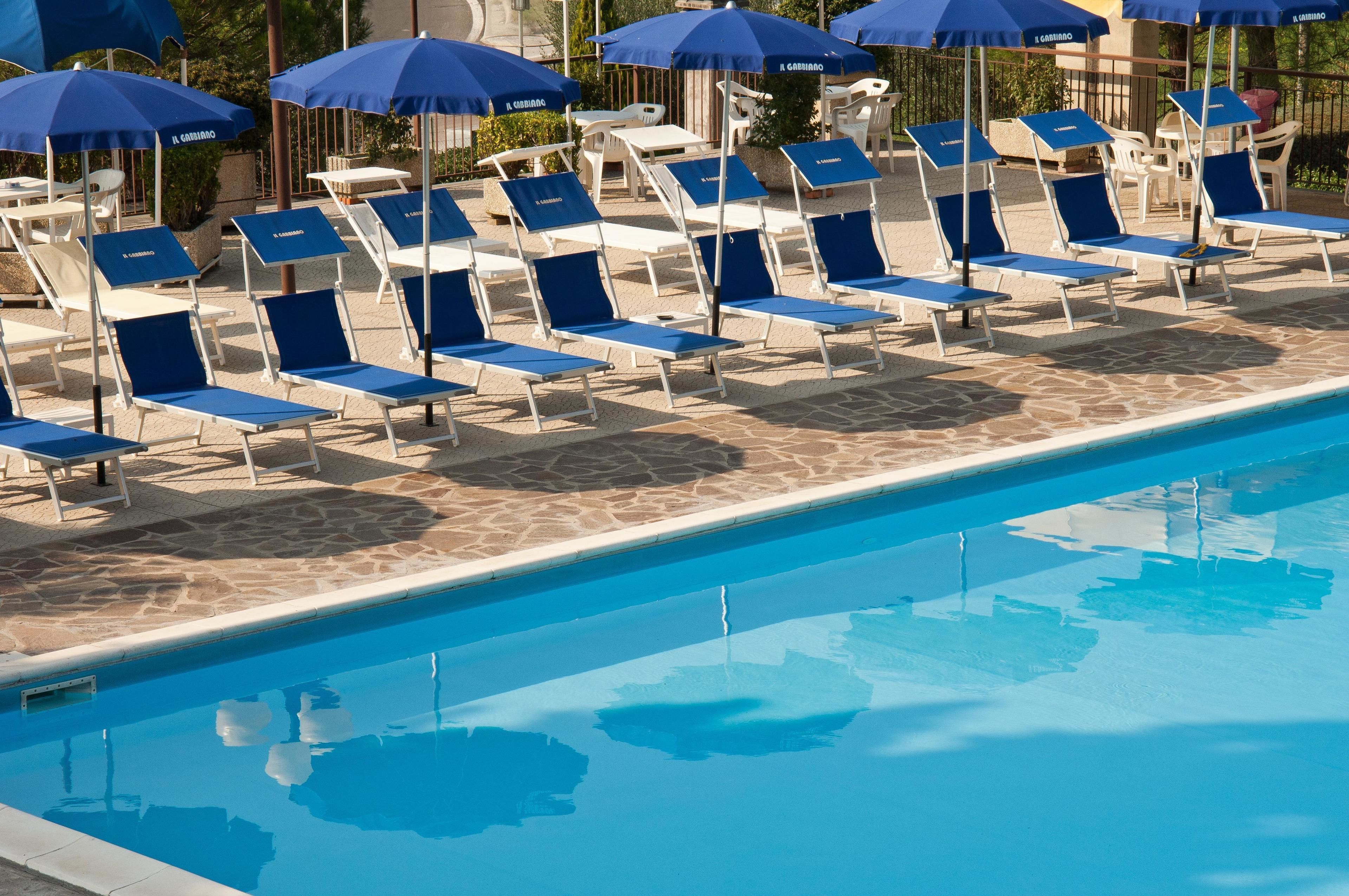 Zona junto a la piscina con sillas de descanso y sombrillas.