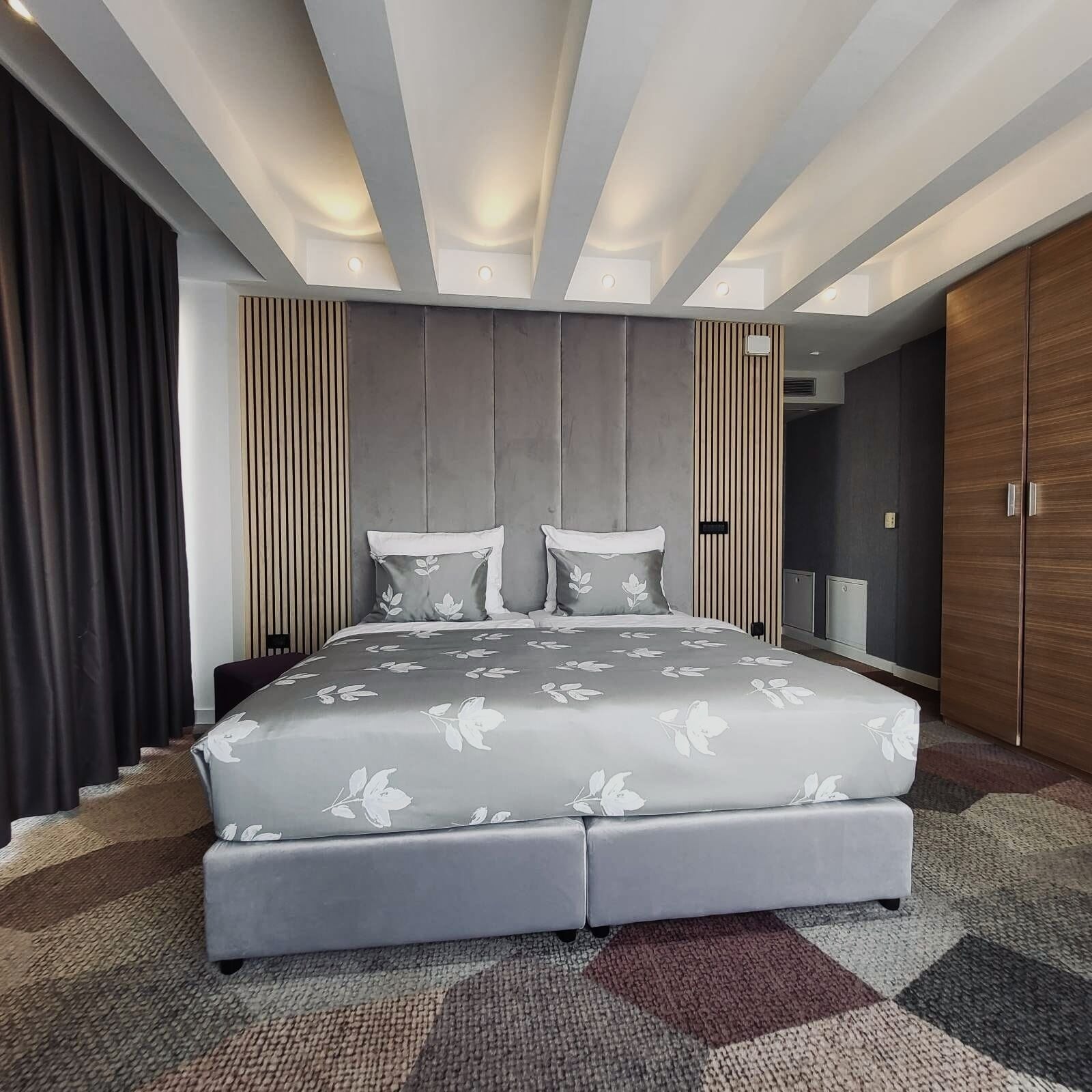 A modern bedroom with a large bed, a wardrobe, and a built-in TV.
