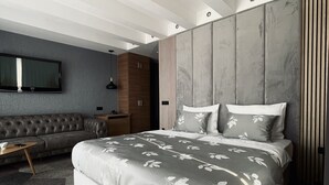 Ein modernes Schlafzimmer mit einem großen Bett, einer Couch und einem Fernseher.