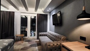 Ein modernes Wohnzimmer mit einer Eckcouch, einem Holztisch und einem an der Wand montierten Fernseher.