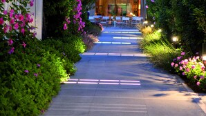 A pathway leading to a building with outdoor seating and a glass facade. - Union Lido Art & Park Hotel (Cavallino-Treporti)