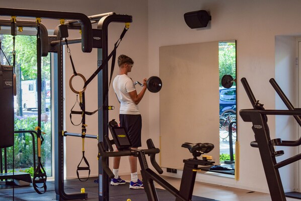 Un gimnasio con varios equipos de ejercicio, incluyendo una estructura para sentadillas y una caminadora.