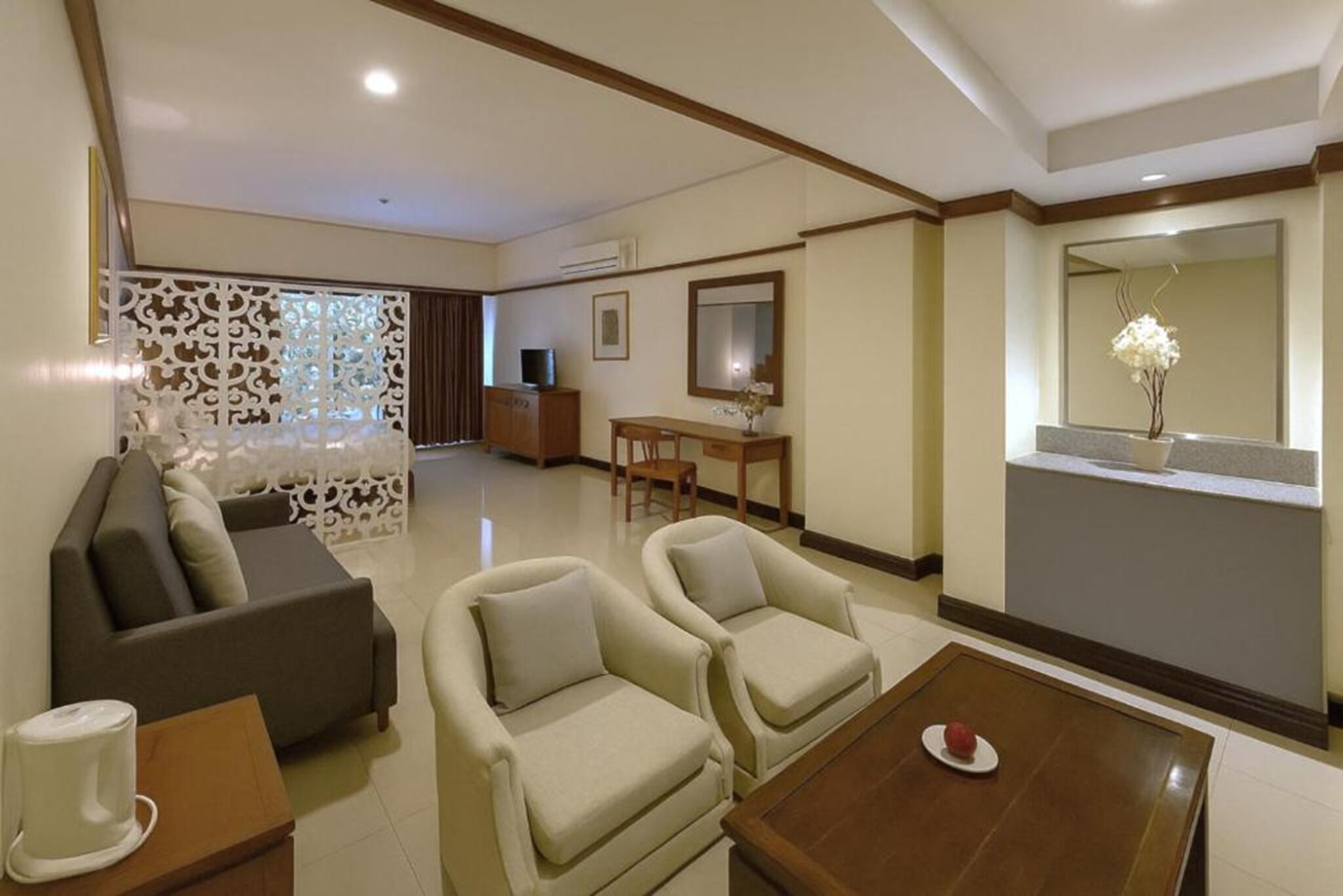 A modern living room with a sofa, two armchairs, a coffee table, and a dining area with a table and chairs.
