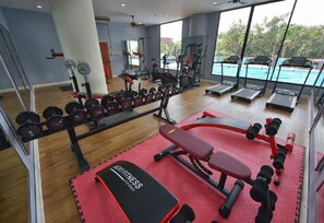 A gym with various exercise equipment, a bench, and a red mat.