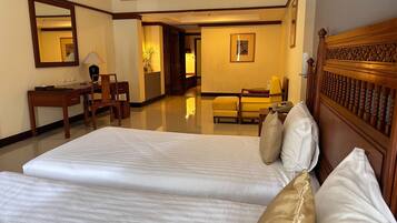 A hotel room with two beds, a desk, a chair, a mirror, and a framed picture on the wall.