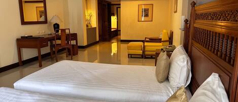A hotel room with two beds, a desk, a chair, a mirror, and a framed picture on the wall.