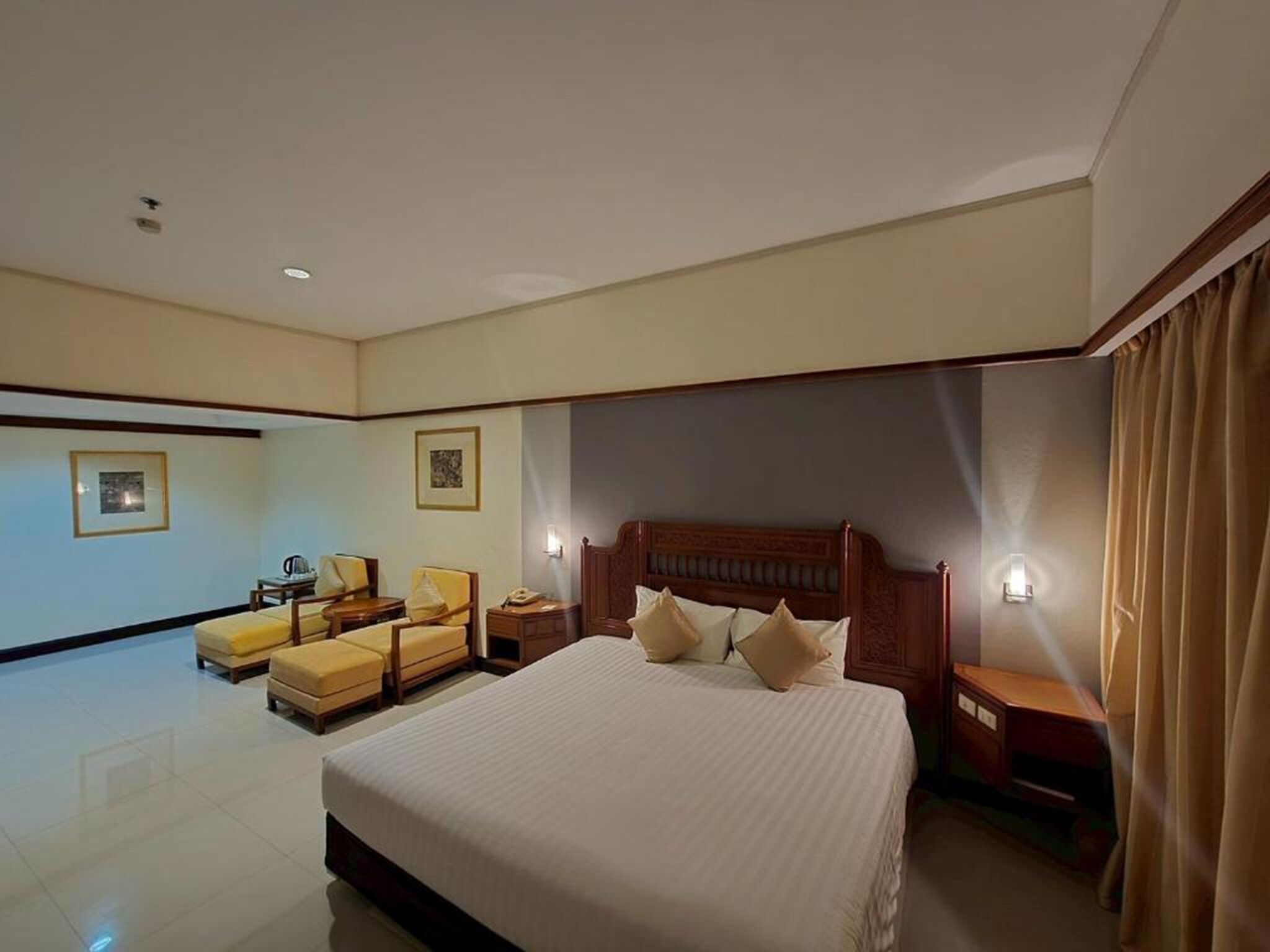 A hotel room with a large bed, two bedside tables, a chair, and a small table.