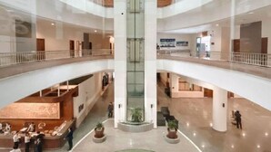 Un atrio de varios niveles con una fuente central, barandillas de vidrio y un diseño moderno.
