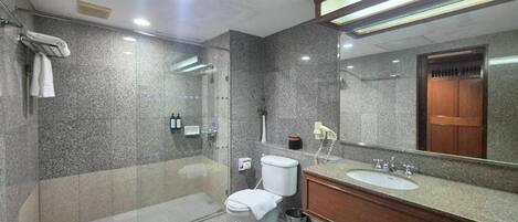 Een moderne badkamer met een douchecabine van glas, een wit toilet en een houten wastafelmeubel met een wastafel.