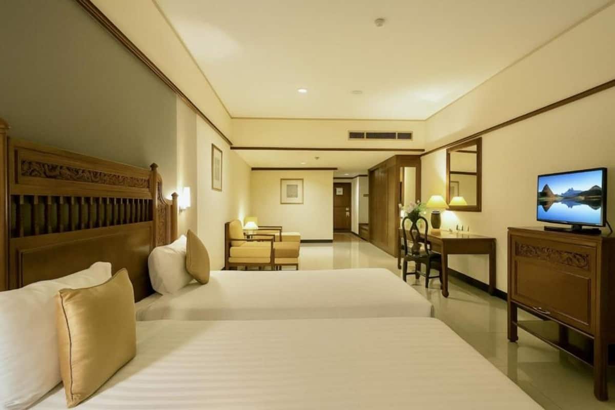 Habitación de hotel con una cama grande, un escritorio, una silla, un televisor y un espejo.