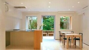A modern kitchen with a central island, a dining area with a table and chairs, and large windows providing views of greenery. - Palazzo Soderini (Venice)