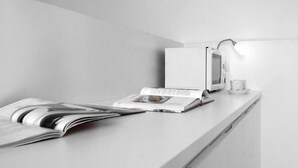 A modern kitchen with a white countertop, a microwave, a coffee maker, and a magazine. - Palazzo Soderini (Venice)