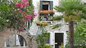 A stone building with a balcony adorned with potted plants and flowers. - Palazzo Soderini (Venice)