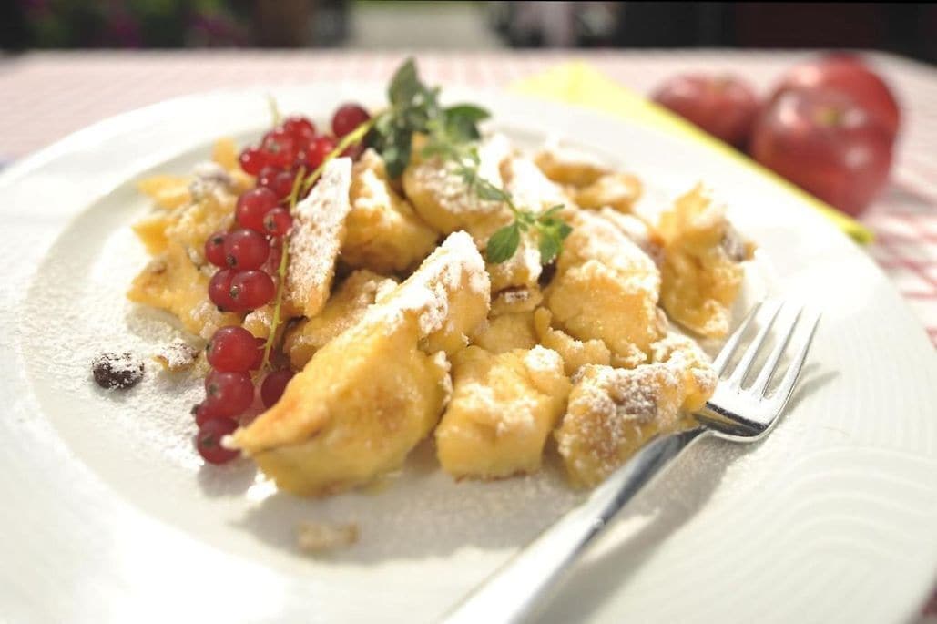 A plate of food with red currants and a sprig of herb.