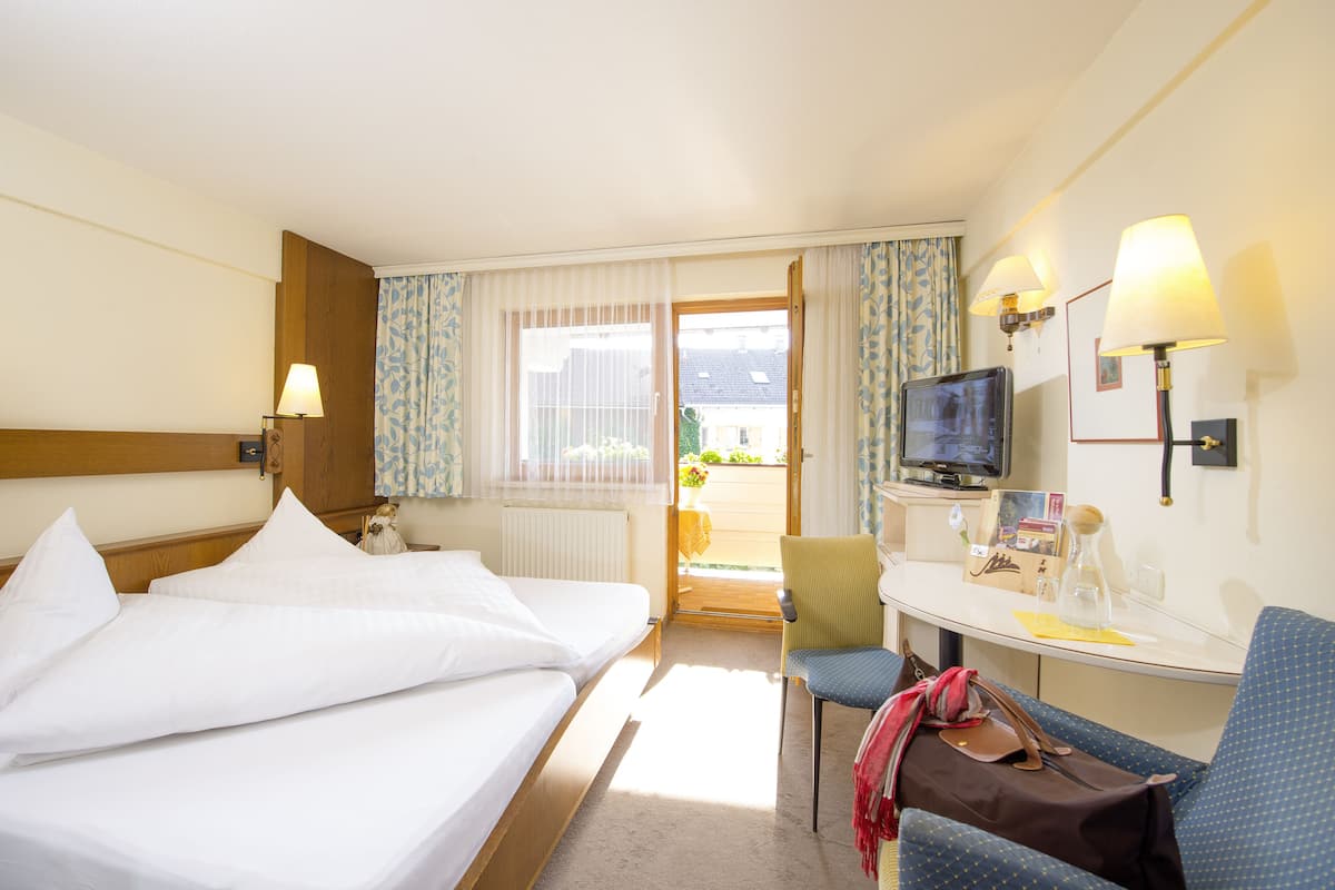 A hotel room with two beds, a desk, a chair, a television, and a window with curtains.