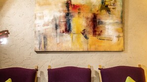 A room with a purple sofa, a glass of wine, a book, and a candle on a table. - Hotel Maximilian (Ehenbichl)