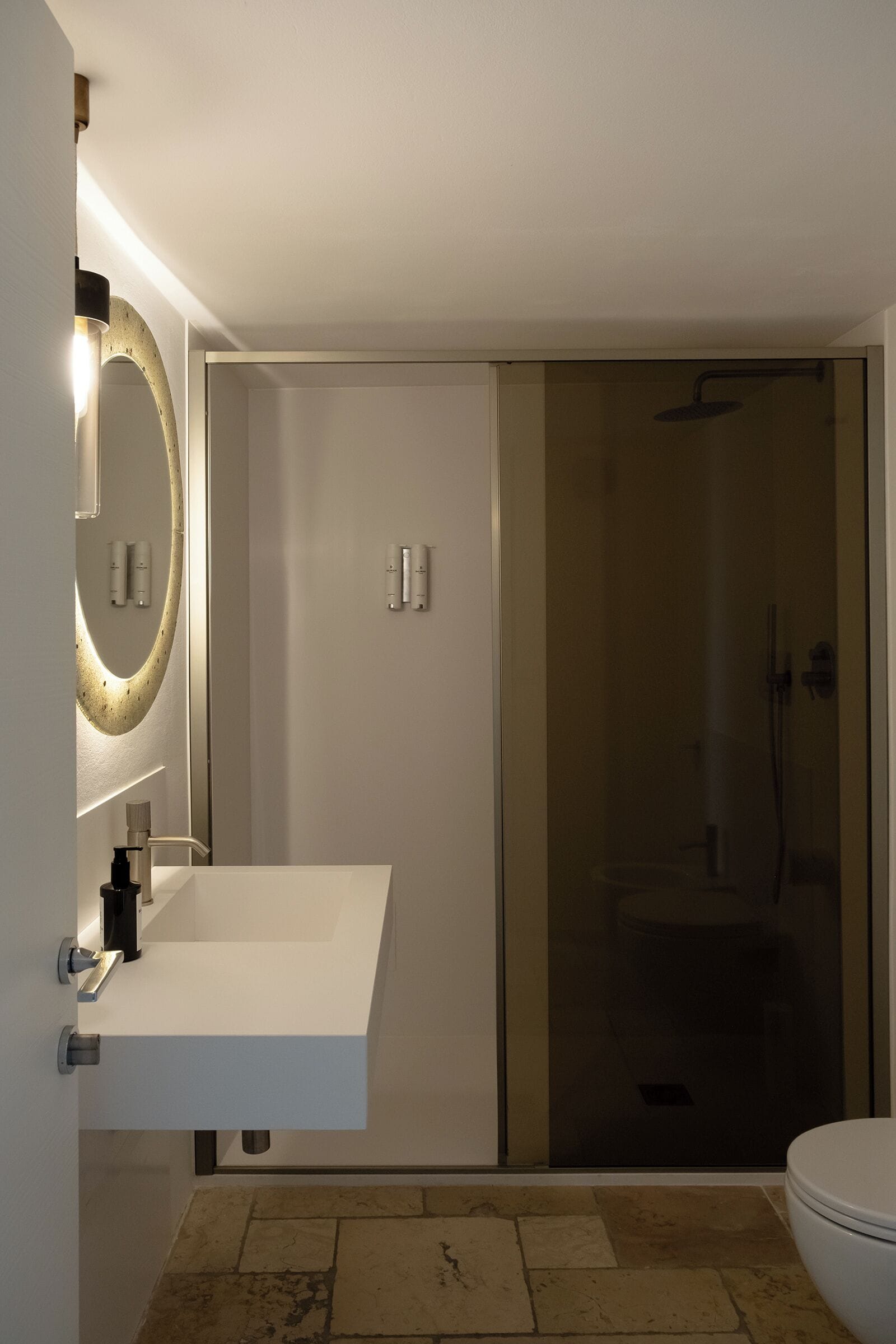 A modern bathroom with a white sink, a large mirror, and a glass-enclosed shower.