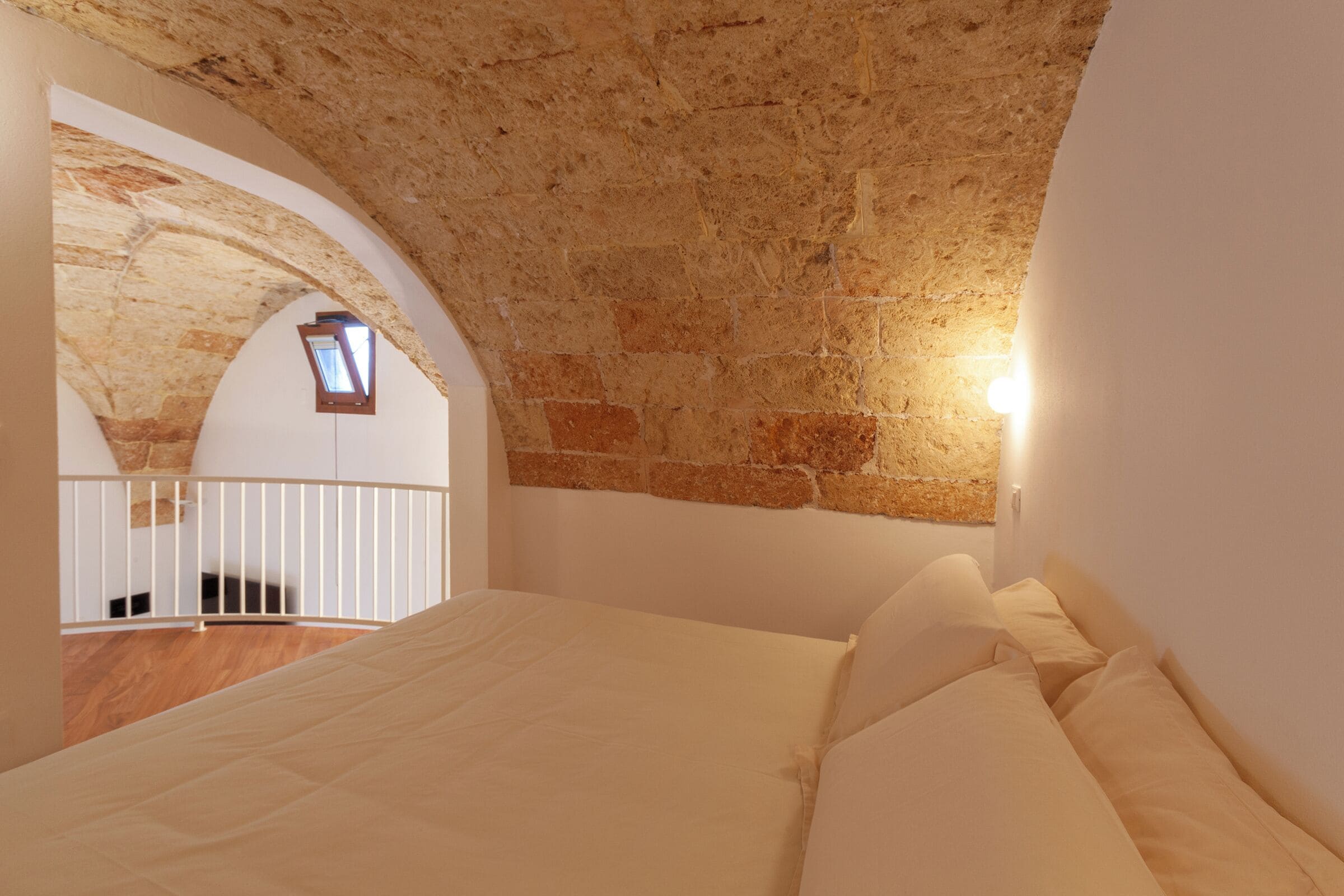 A bedroom with a stone ceiling, a small skylight, and a balcony.
