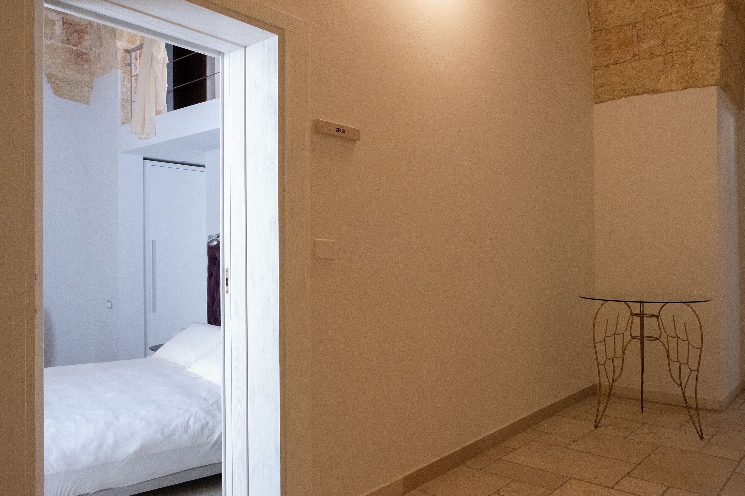 Un dormitorio con cama, armario y una mesita de noche con diseño alado.