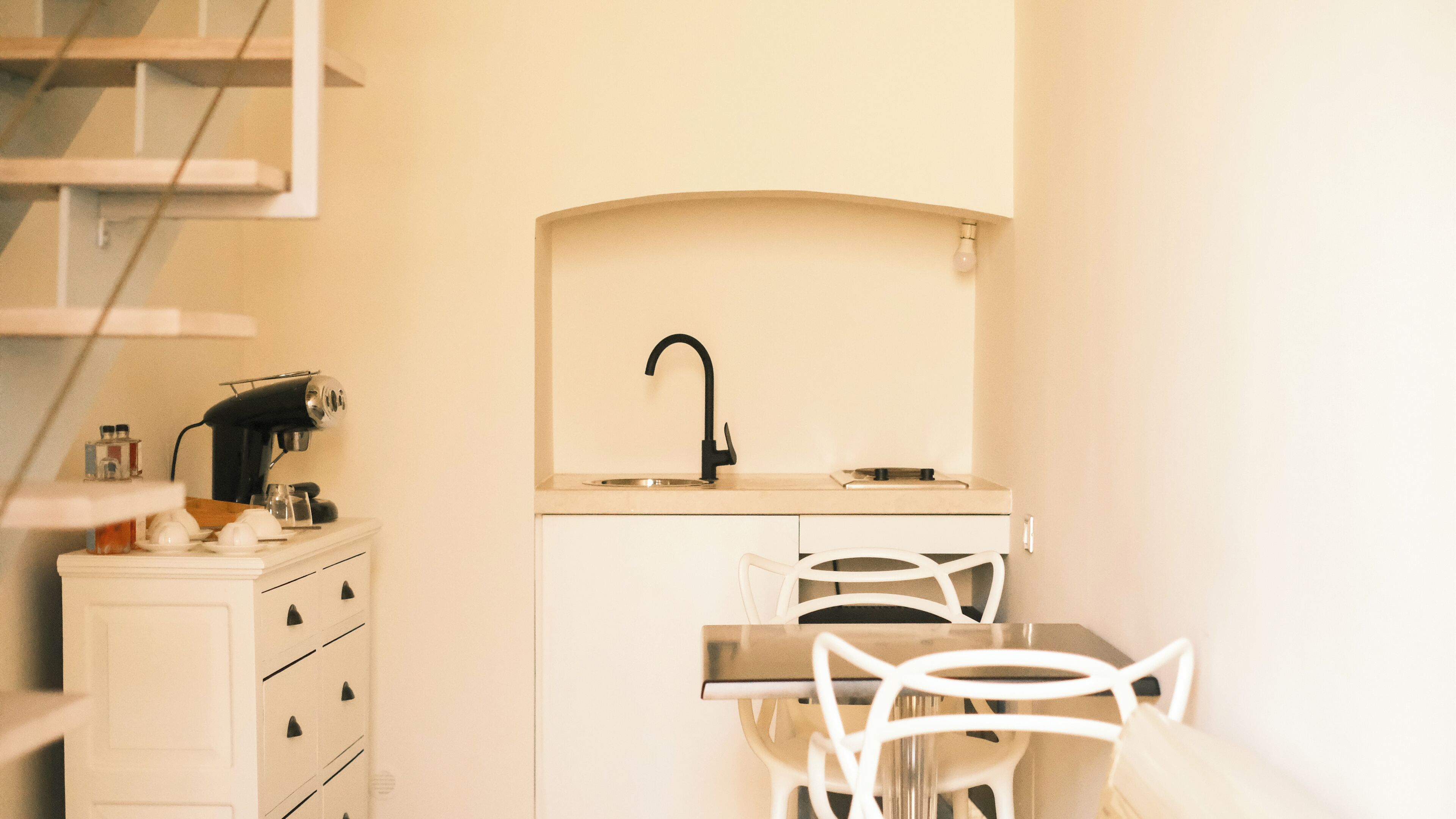 A compact kitchen with a sink, a small countertop, and a dining area with chairs.