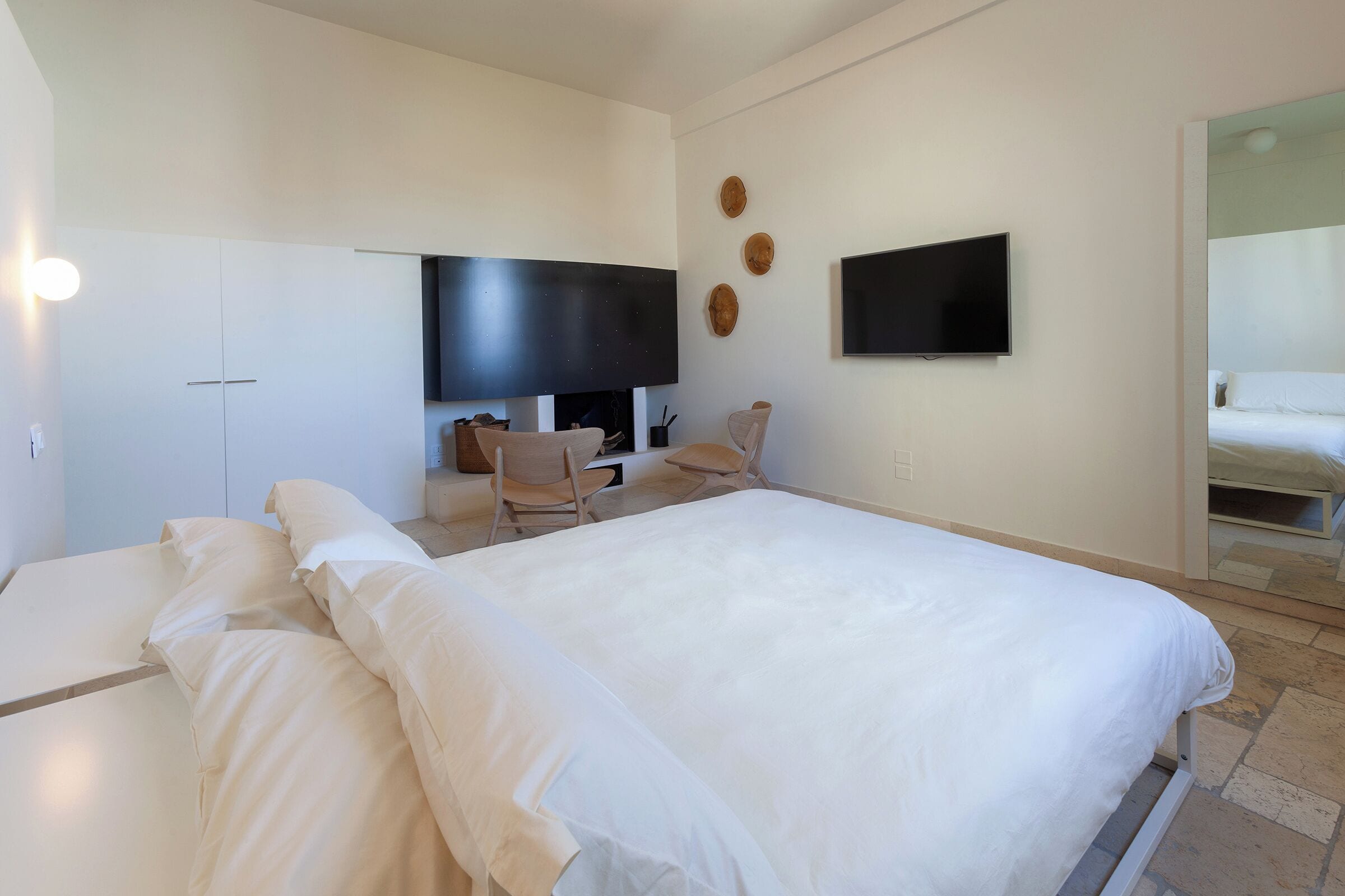 Een hotelkamer met een groot bed, een bureau met stoel, een flatscreen-tv en een spiegel.