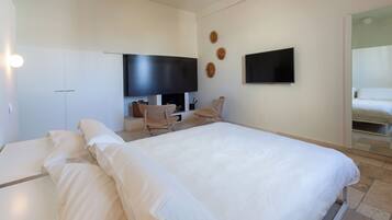 Een hotelkamer met een groot bed, een bureau met stoel, een flatscreen-tv en een spiegel.