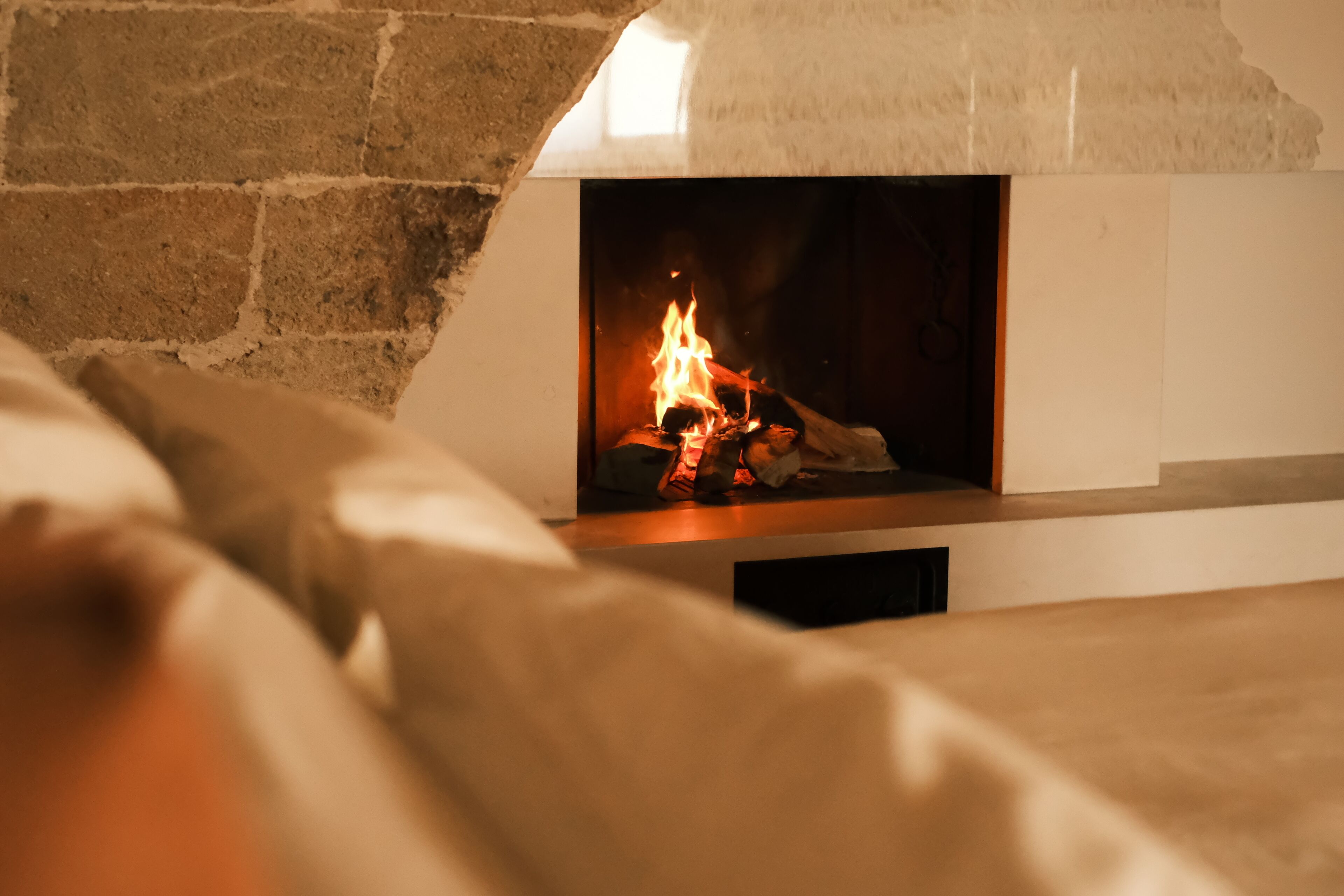 A fireplace with visible logs and flames, a stone wall, and a white mantelpiece.