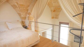 A bedroom with a bed, a nightstand, a window, and a staircase.