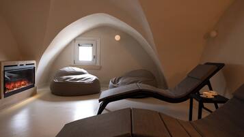 A cozy, modern room with a fireplace, a comfortable lounge chair, and a small window.